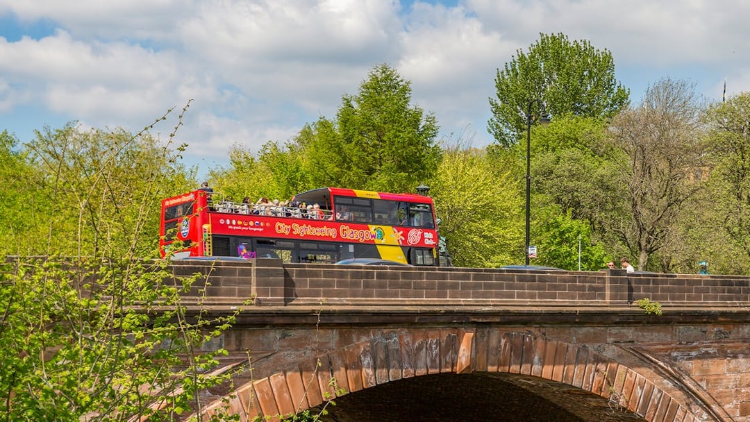 Open-top sightseeing bus crossing a bridge in Glasgow.