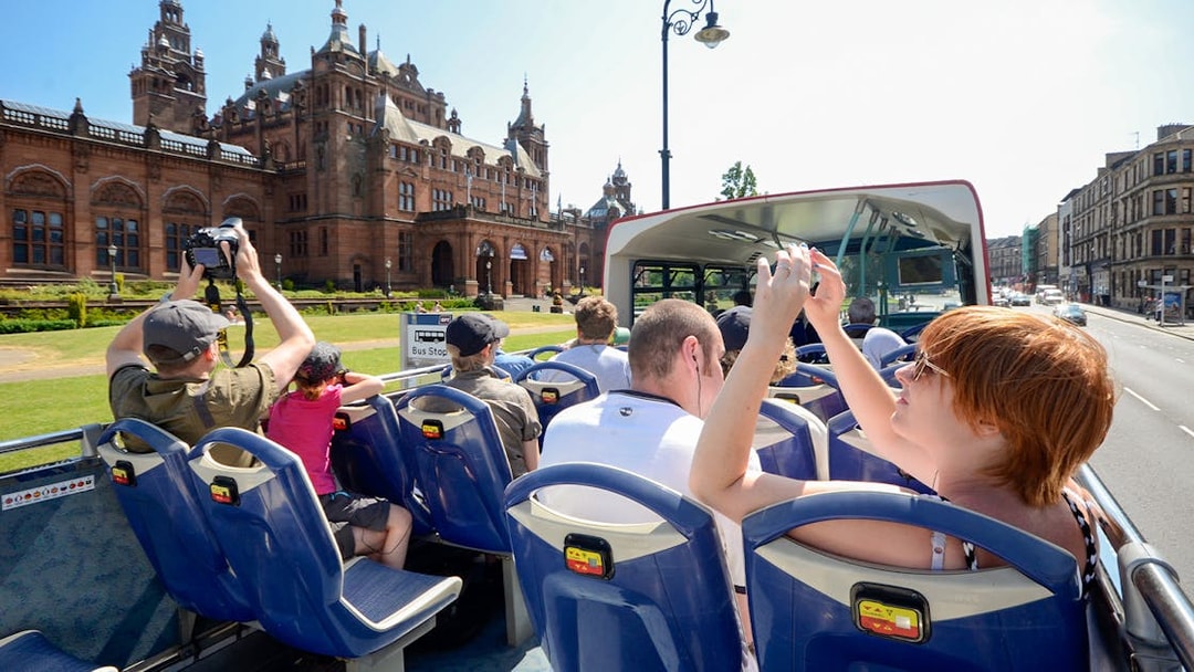 Open-top bus tour passing Kelvingrove Art Gallery in Glasgow.