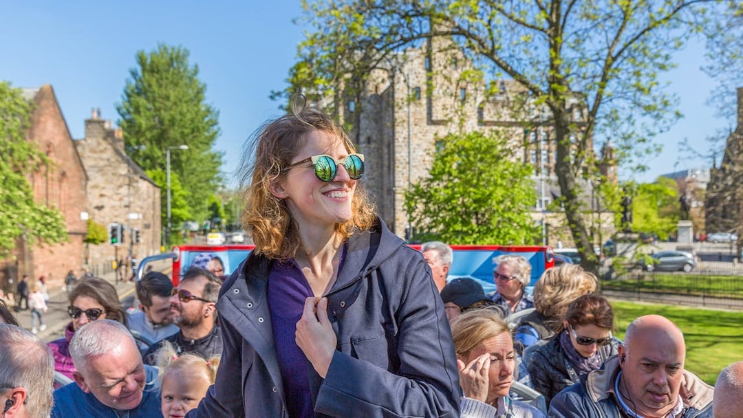 Tourists enjoying a sunny day on a hop-on hop-off bus tour in Glasgow.