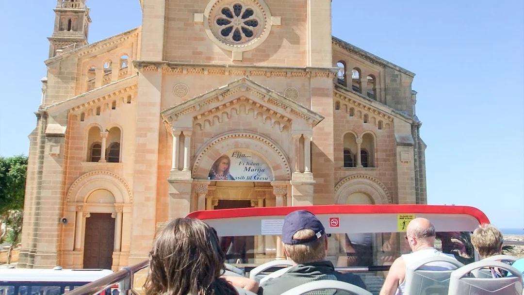 Open-top bus tour passing Ta' Pinu Basilica in Gozo.