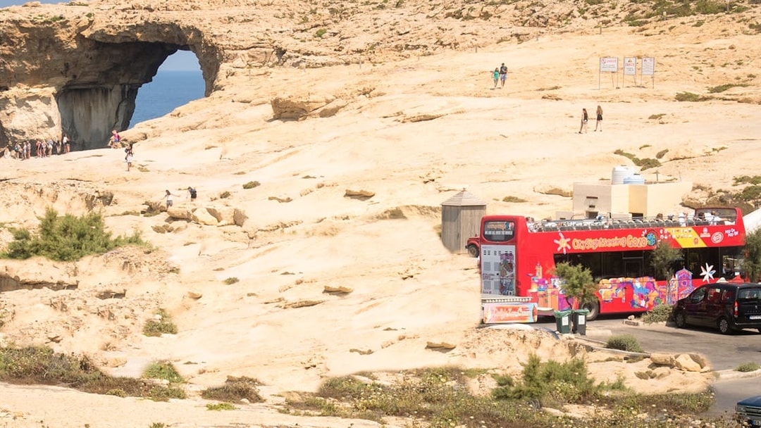 Gozo sightseeing bus near Azure Window rock formation, Malta.