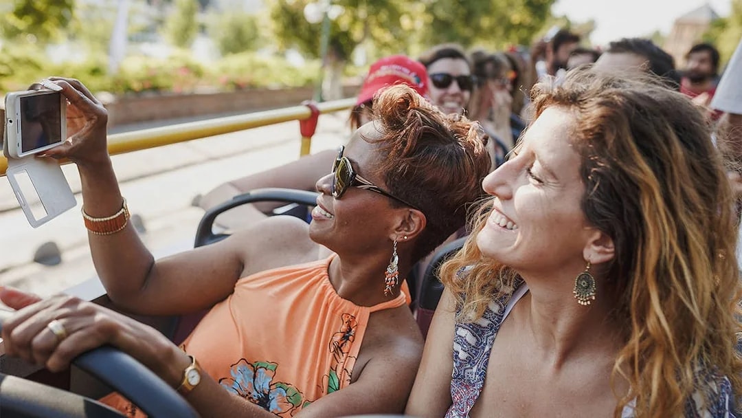 Tourists on a Milan Hop-On Hop-Off bus taking photos, enjoying city landmarks.