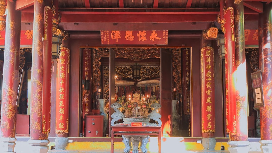 Temple entrance with ornate red columns and golden inscriptions in Hanoi.
