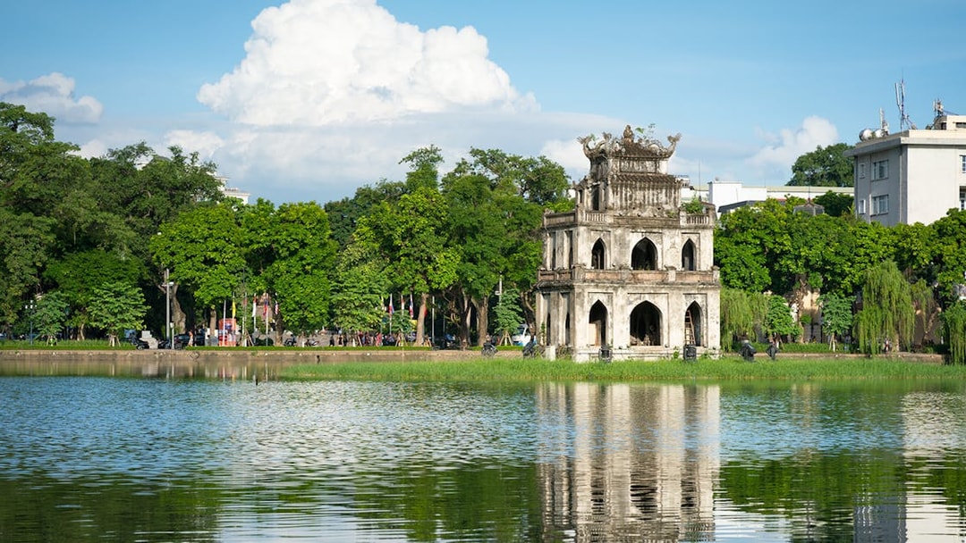 Hop-on Hop-off bus near Hoan Kiem Lake, Hanoi, with Turtle Tower in view.