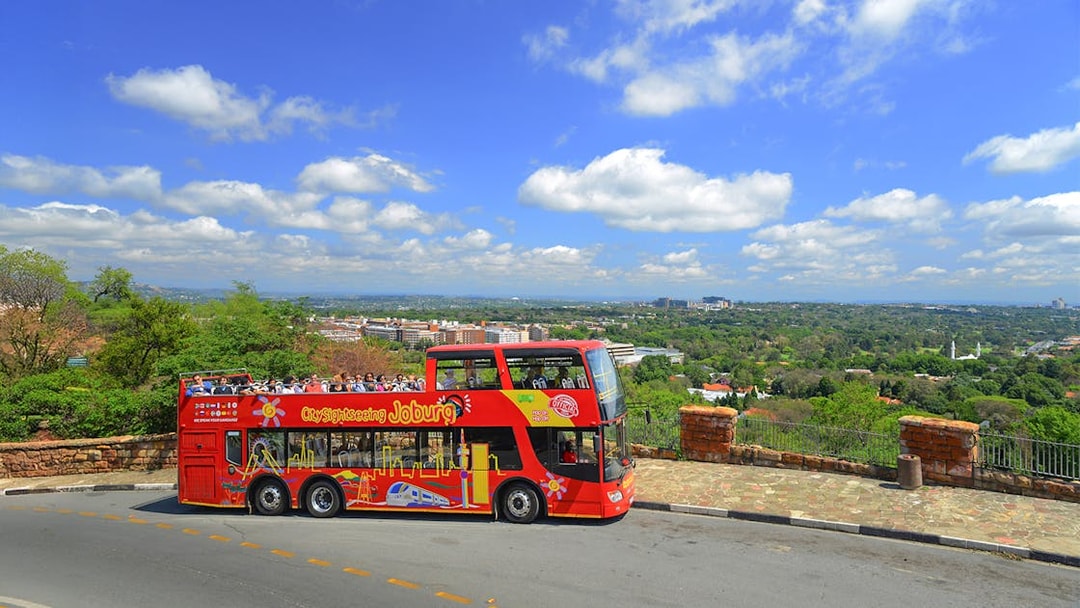 City sightseeing bus on a hill overlooking Johannesburg skyline.