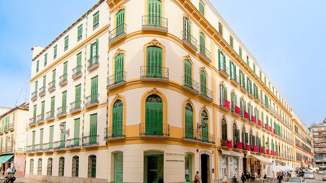 Facade of Picasso's Birthplace Museum in Málaga with green shutters and balconies.