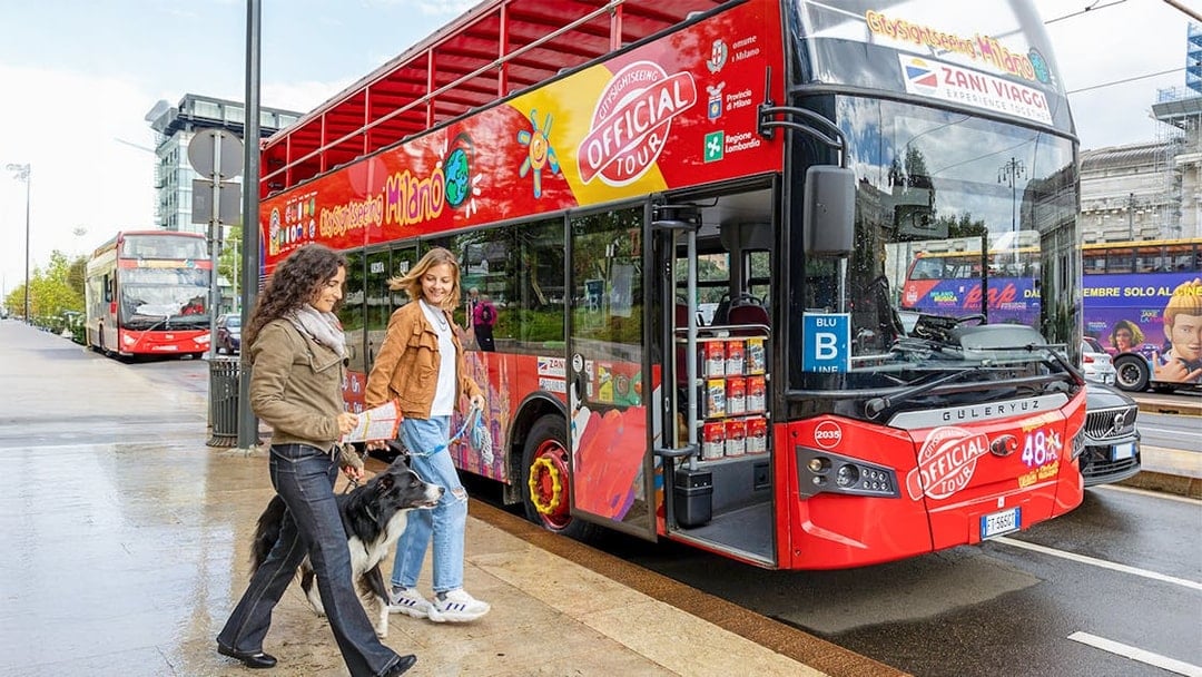 Friends boarding City Sightseeing Milan Hop On Hop Off Bus with a dog on leash.