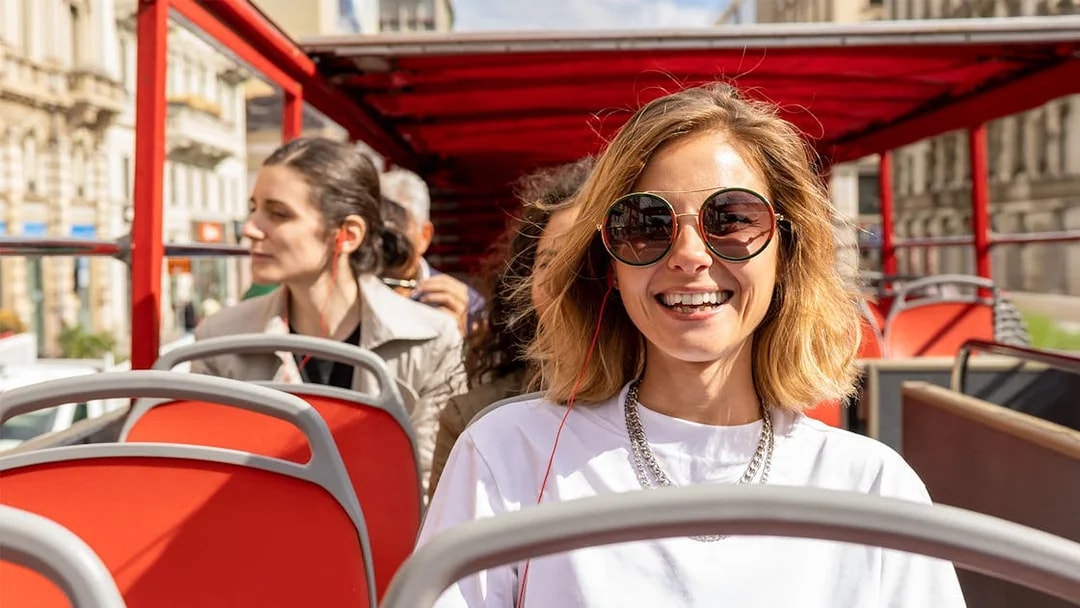 Woman enjoying audio guide on Milan Hop On Hop Off bus tour.