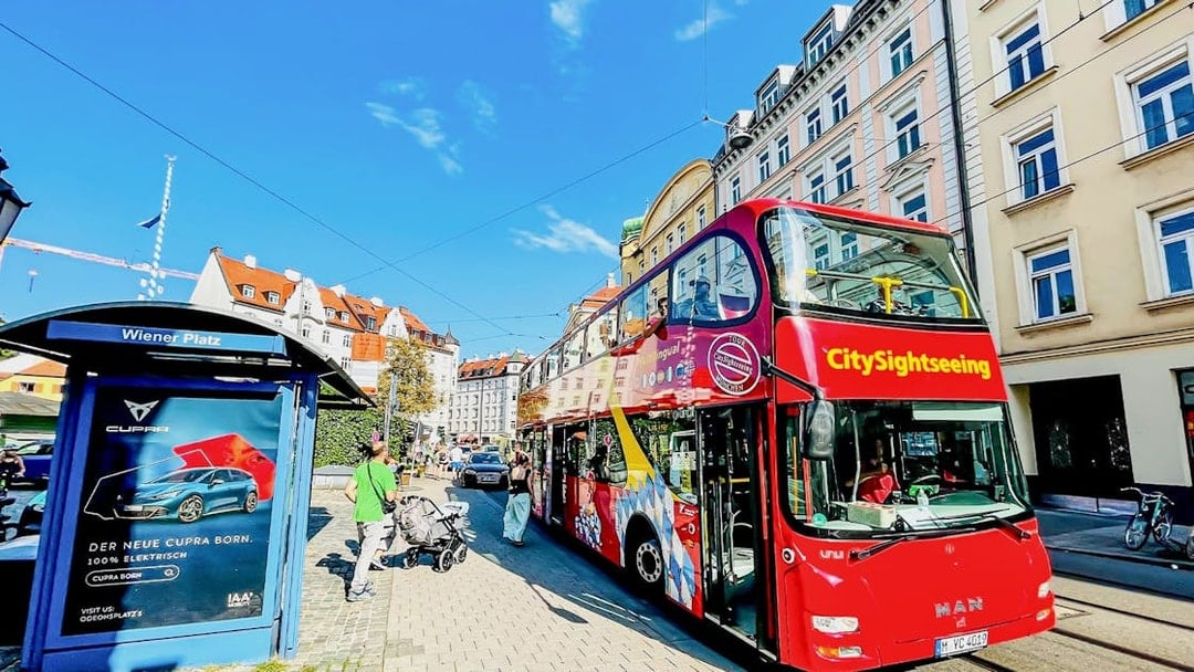 CitySightseeing bus at Wiener Platz with historic buildings in the background.