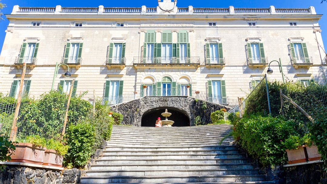 Elegant historic building with green shutters and stone steps in Naples, Italy.