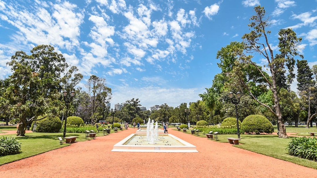 Fountain and pathways in English garden, Palermo, surrounded by trees and benches.