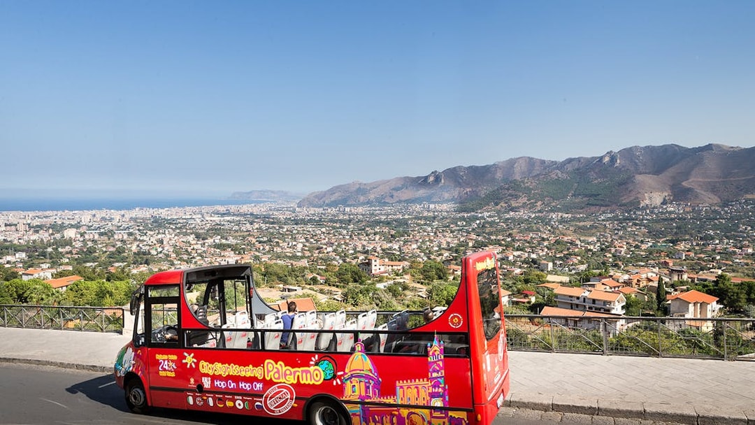 Palermo hop-on hop-off bus with city and mountain view in the background.