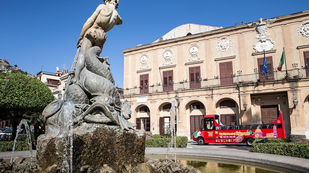 Palermo fountain with City Sightseeing hop-on hop-off bus in front of historic building.