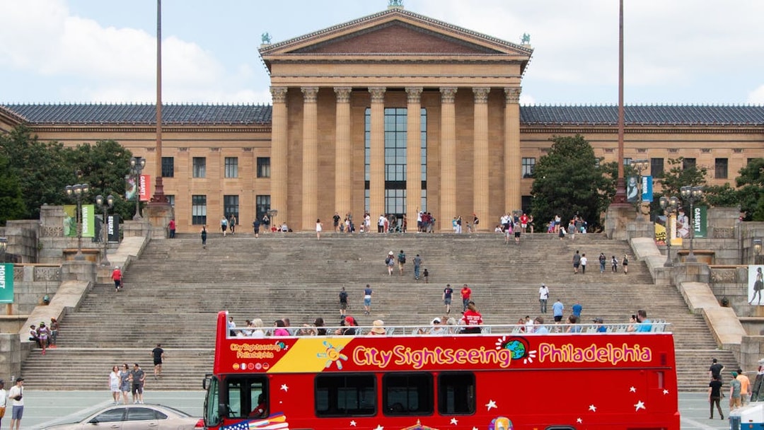 Red sightseeing bus in front of the Philadelphia Museum of Art steps on a hop-on-hop-off tour.