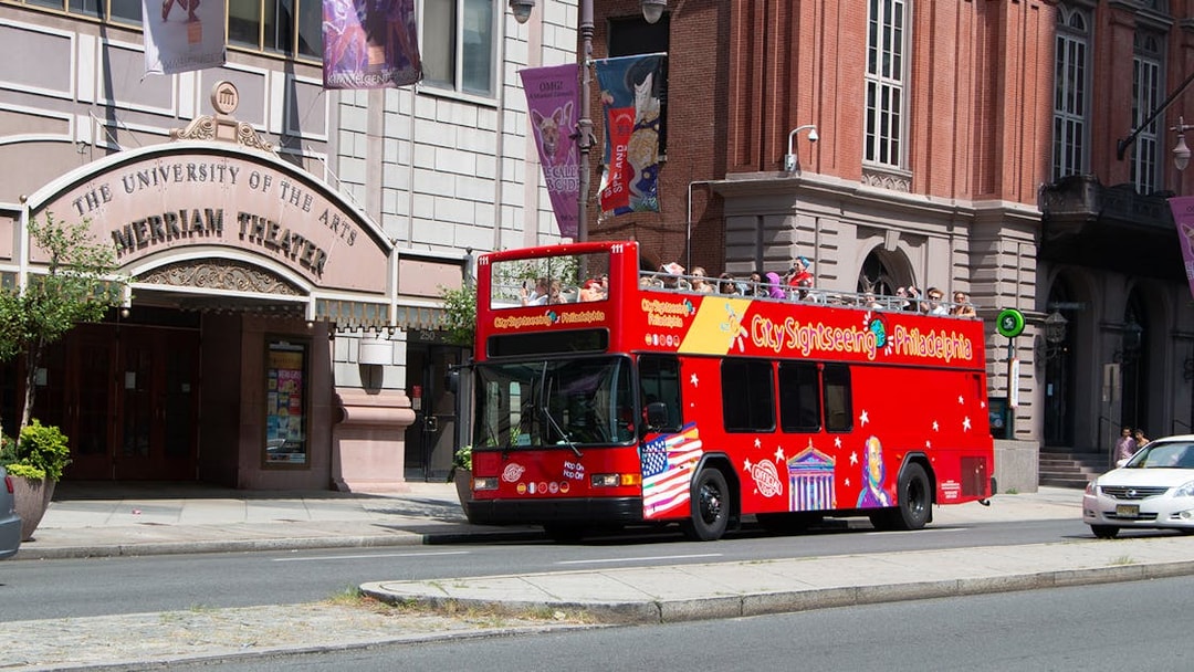 Red double-decker bus on Philadelphia Hop-On-Hop-Off Tour passing Merriam Theater.