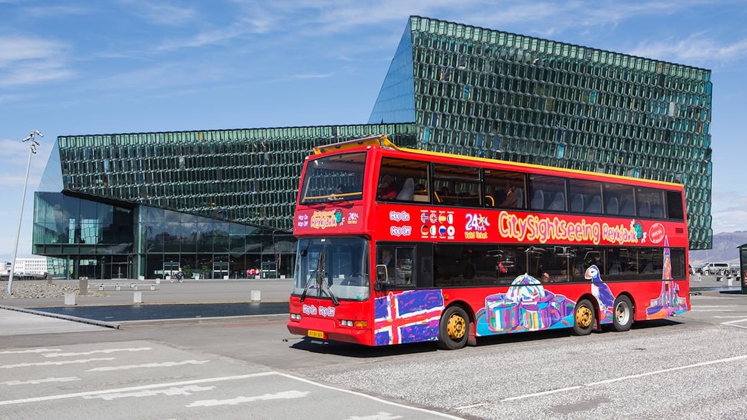 Red double-decker bus in front of Harpa Concert Hall, Reykjavik Hop-On Hop-Off Tour.