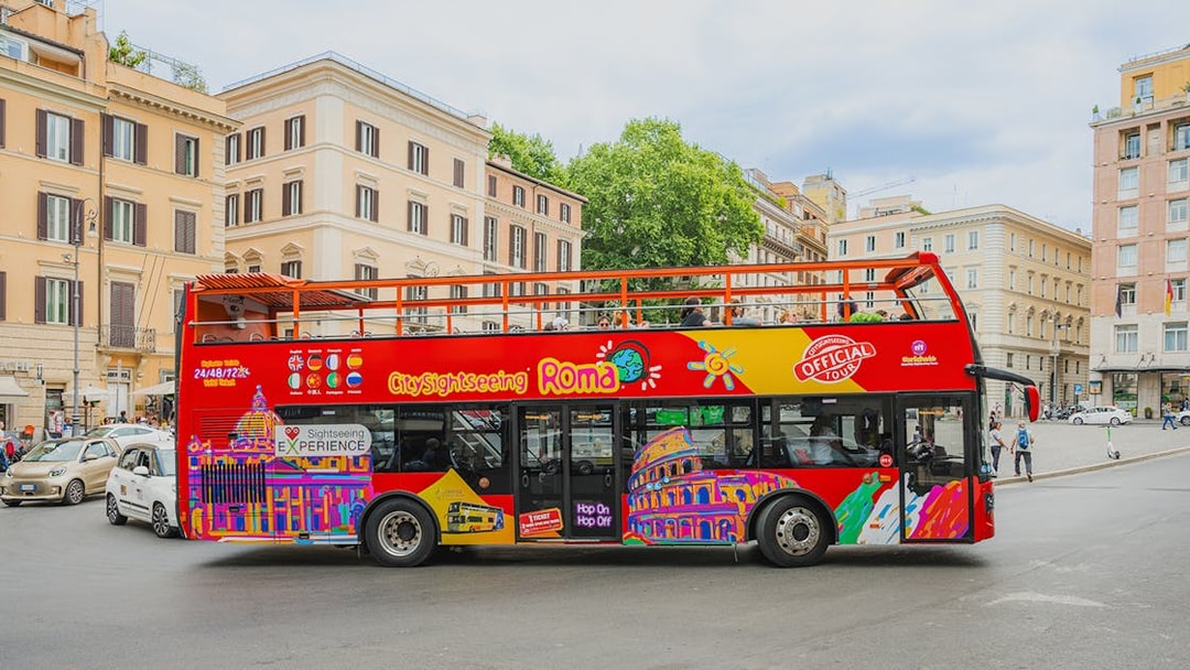 City Sightseeing bus in Rome with colorful graphics parked near historic buildings.