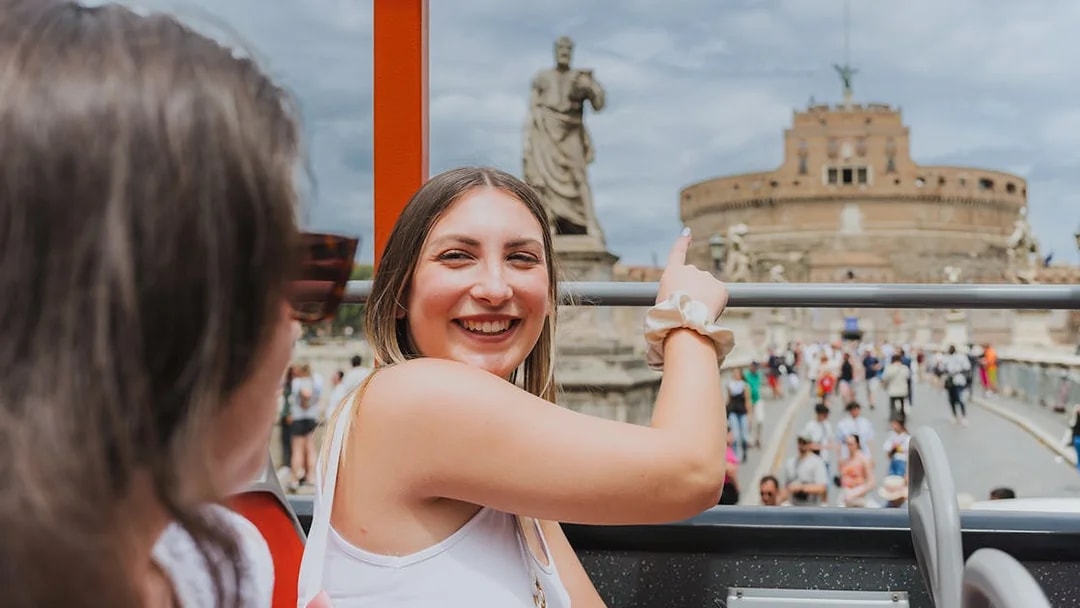 Tourists on a bus pointing at Castel Sant'Angelo in Rome during a city sightseeing tour.