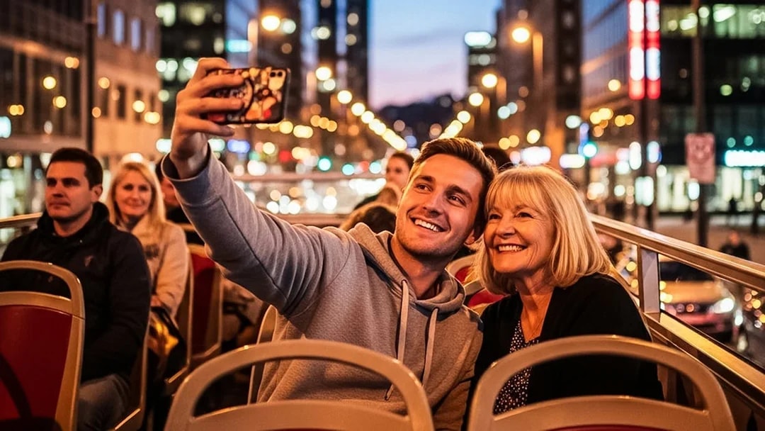 Tourists taking a selfie on a hop-on hop-off bus in a city at night.