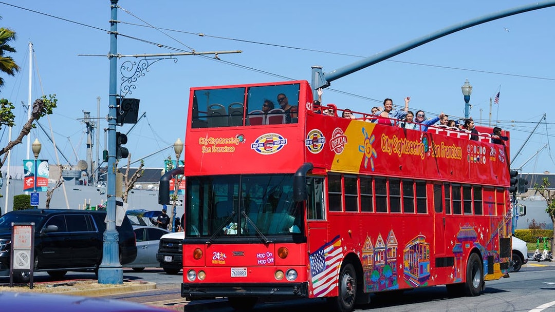 Open-top sightseeing bus in San Francisco with tourists on board.