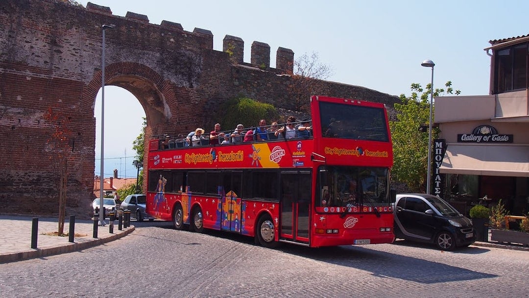 Thessaloniki hop-on hop-off bus near ancient city wall arch.