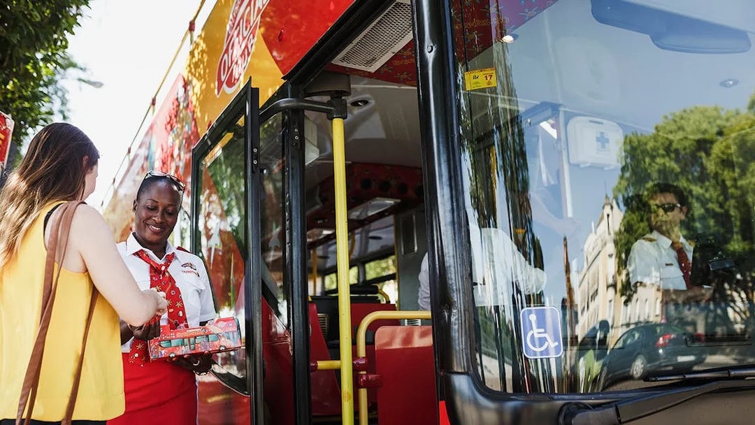 Tourist boarding Thessaloniki hop-on-hop-off bus with guide assisting.