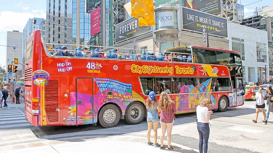 Toronto sightseeing bus at downtown stop with passengers boarding.
