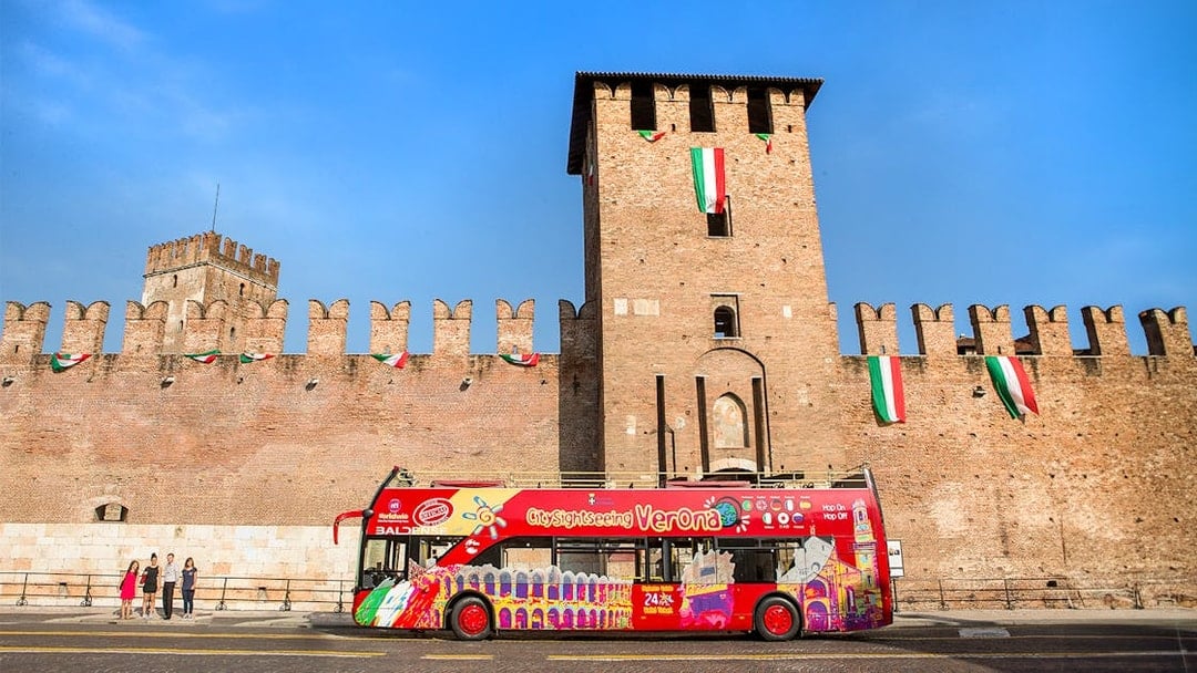Verona sightseeing bus in front of Castelvecchio on a sunny day.