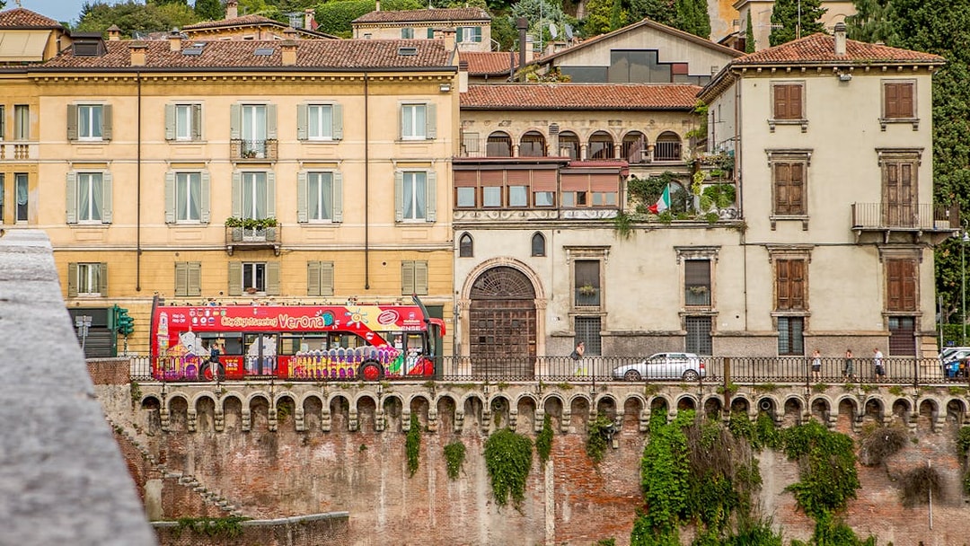Verona sightseeing bus passing historic buildings on a hop-on hop-off tour.