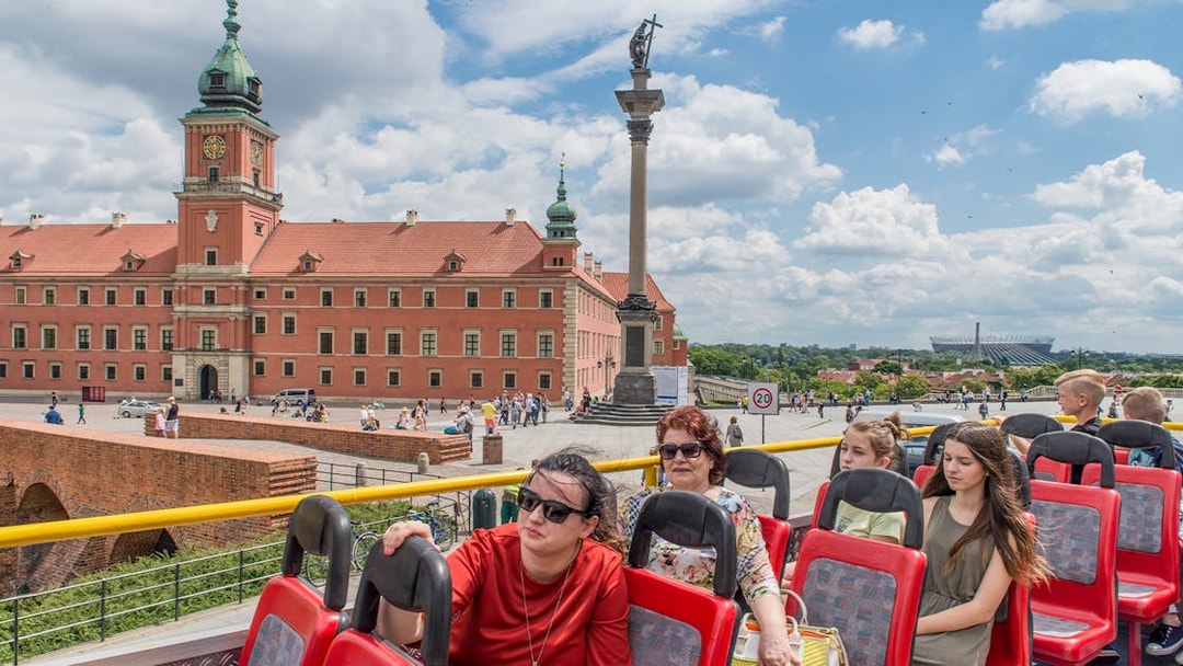 Open-top bus tour passing Warsaw's Royal Castle and Sigismund's Column.