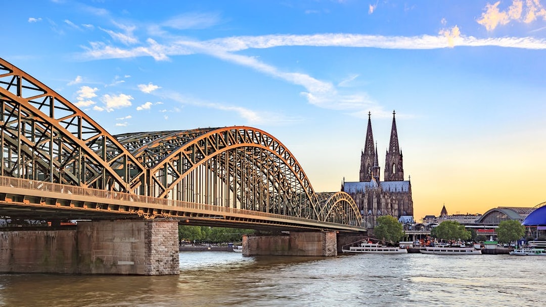 Hohenzollern Bridge over Rhine River with Cologne Cathedral at sunset.