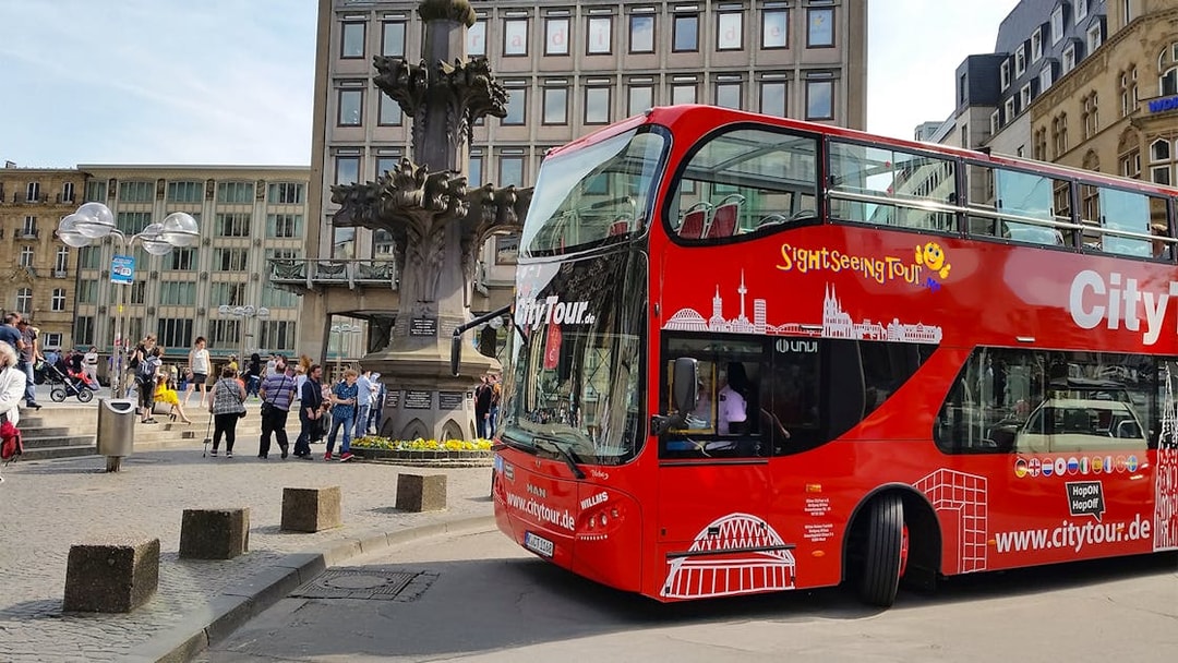 Hop on Hop off City Tour bus in Cologne near historic fountain.