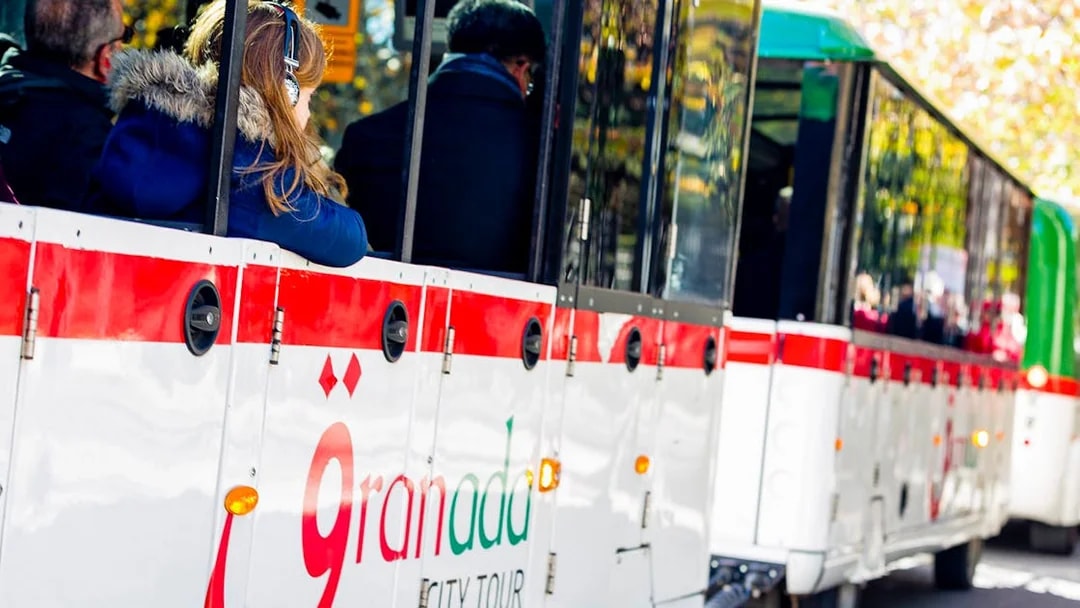 Granada city tour bus with passengers on a hop-on hop-off route.
