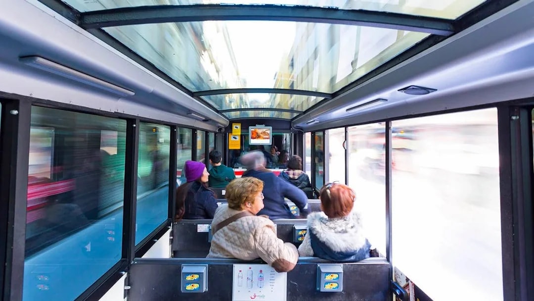 Tourists seated inside a glass-roofed bus in Granada, Spain.