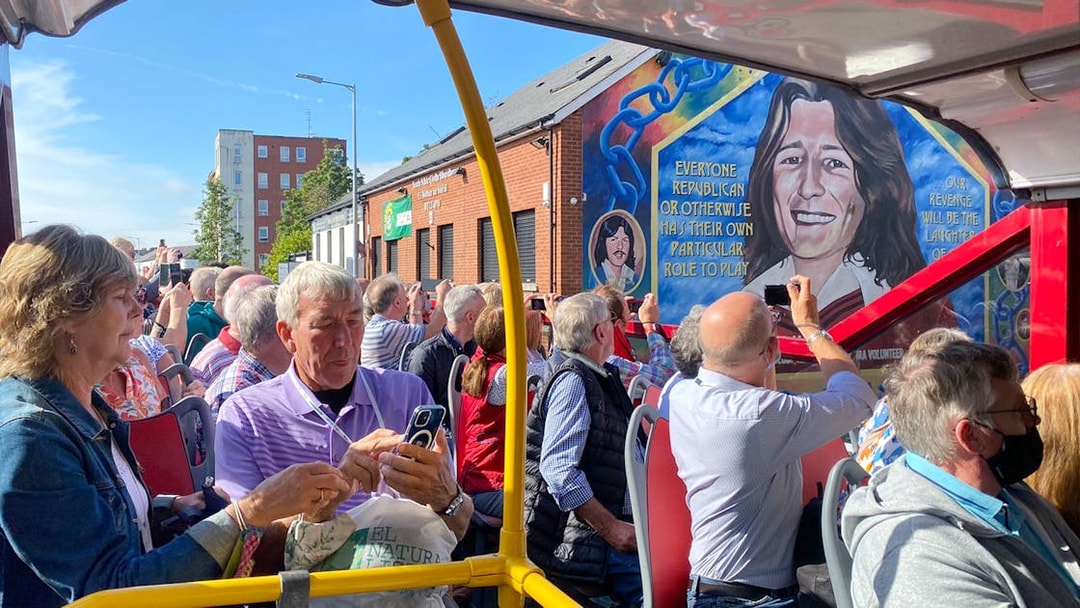 Tourists on a bus tour viewing the Bobby Sands mural on Falls Road, Belfast.