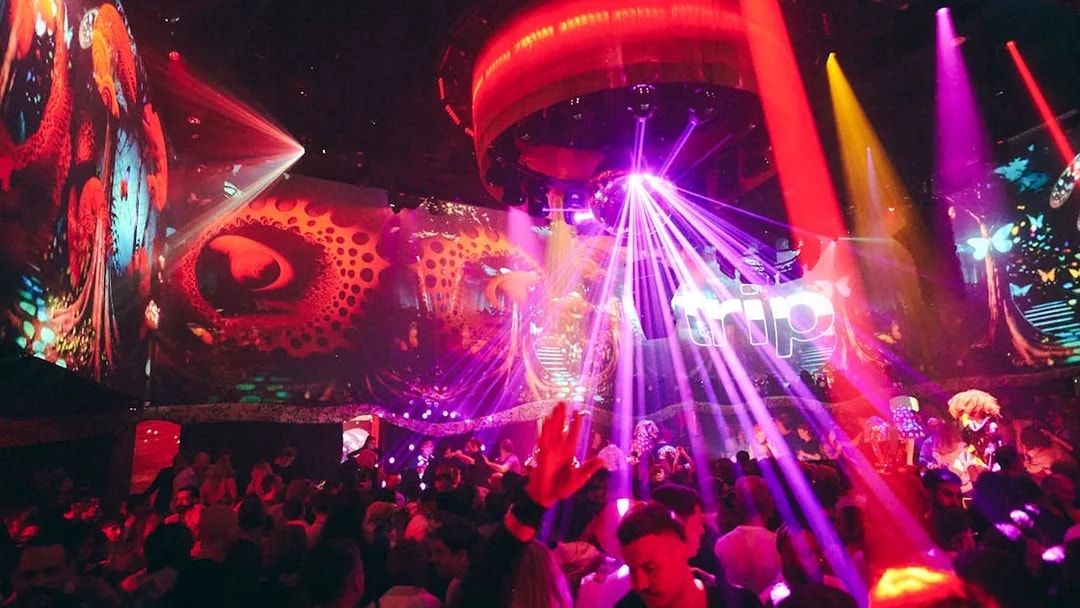 Crowd enjoying vibrant lights and music at TRIP Club Chinois.