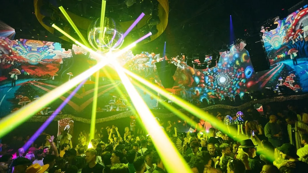 Crowd enjoying vibrant light show at TRIP Club Chinois with colorful psychedelic visuals.