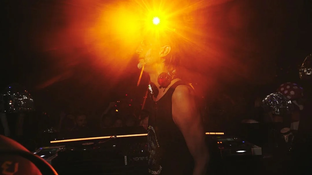 DJ performing at Club Chinois with vibrant lighting effects.