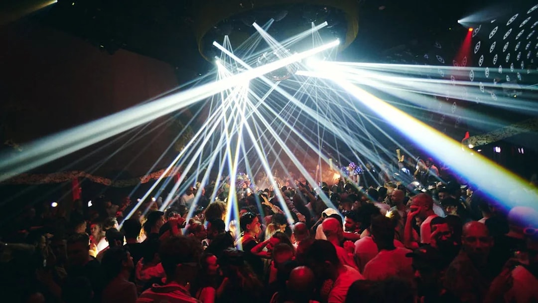 Crowd enjoying vibrant lights at TRIP Club Chinois.