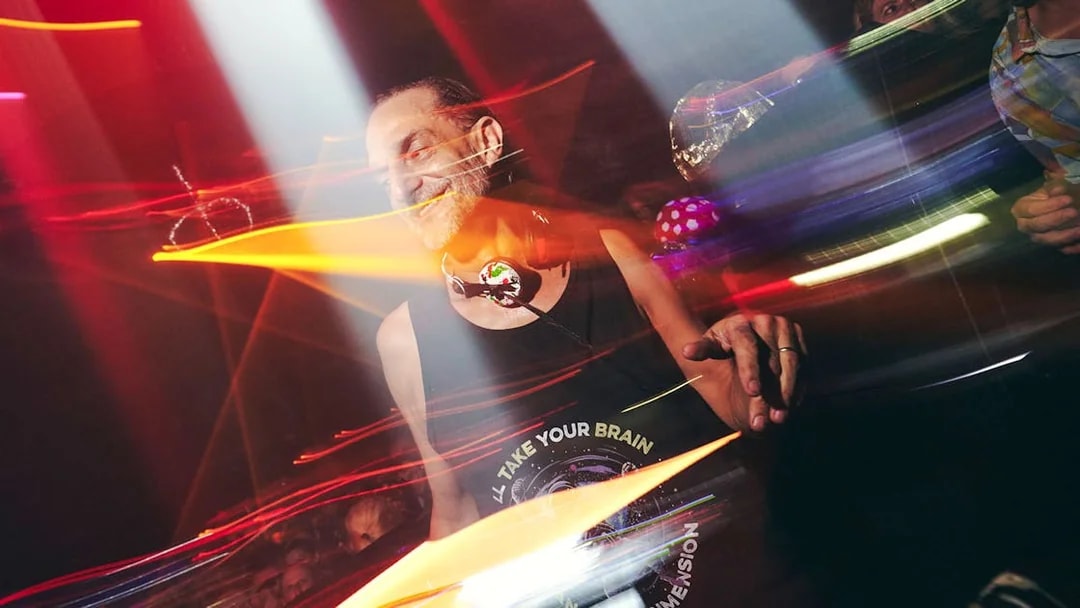 DJ performing at Club Chinois with vibrant lights and crowd.