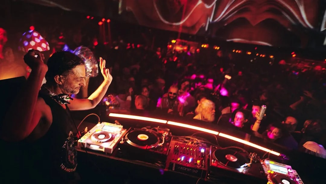 DJ performing at Club Chinois with vibrant crowd and colorful lights.