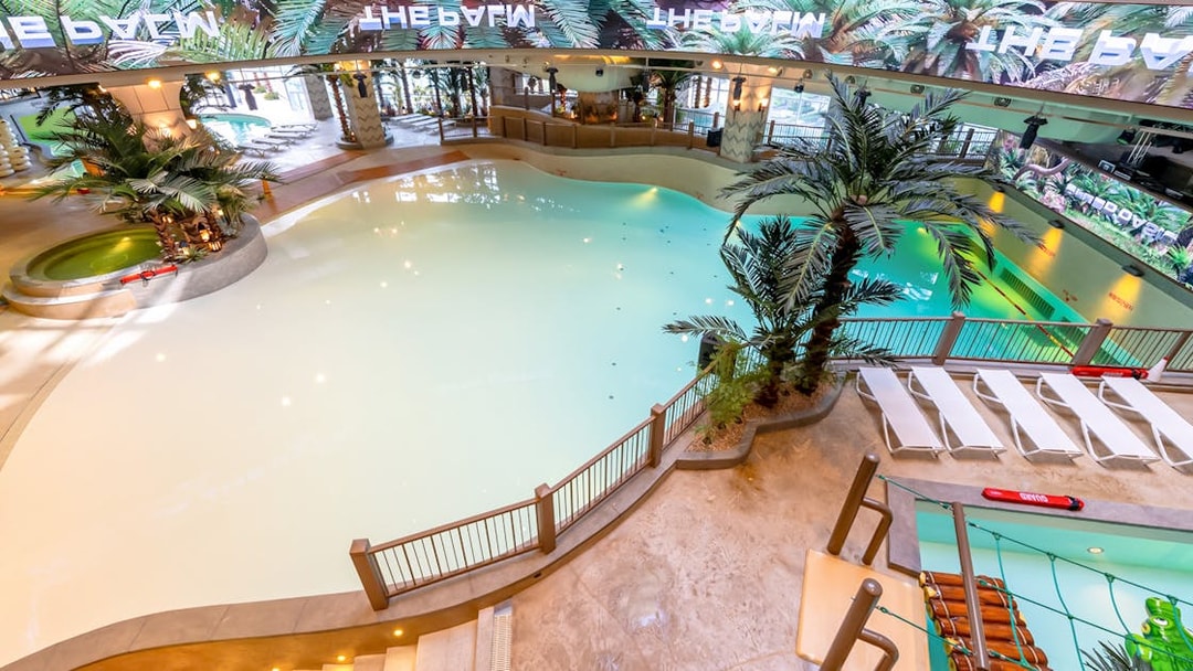 Indoor wave pool at Club D Oasis, surrounded by palm trees and LED screen.
