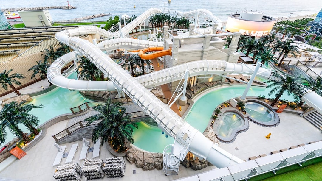 Overhead view of intertwining waterslides at Club D Oasis water park overlooking the sea.