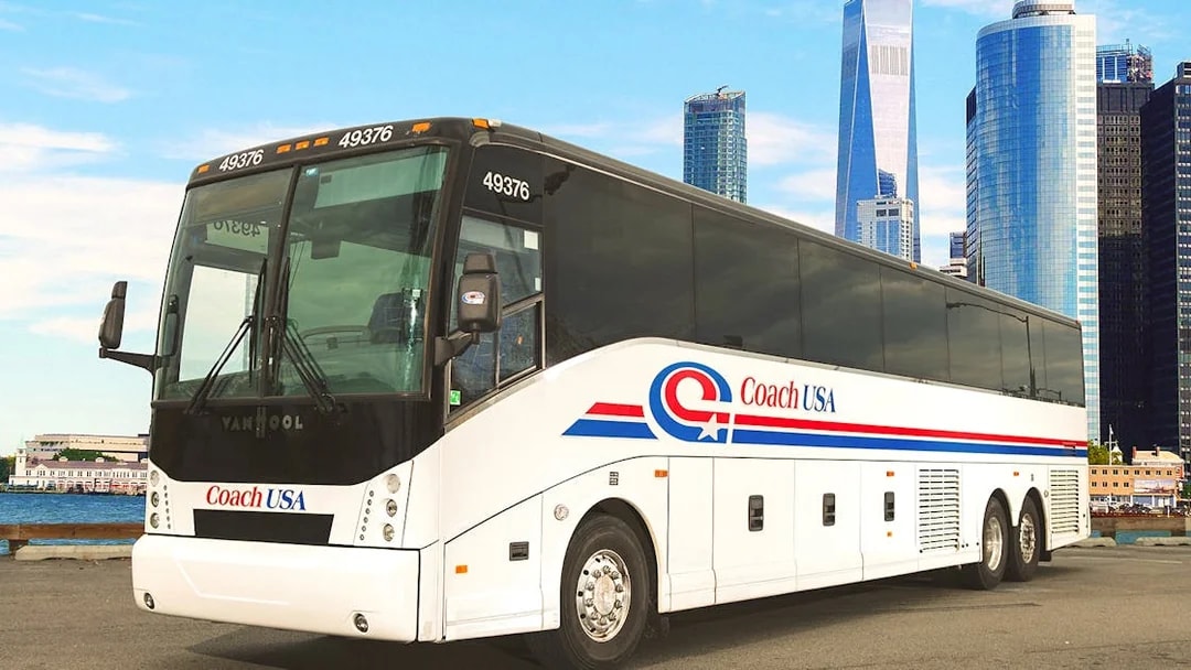 Coach USA bus parked with city skyline in background, route from Chicago O'Hare to Milwaukee.