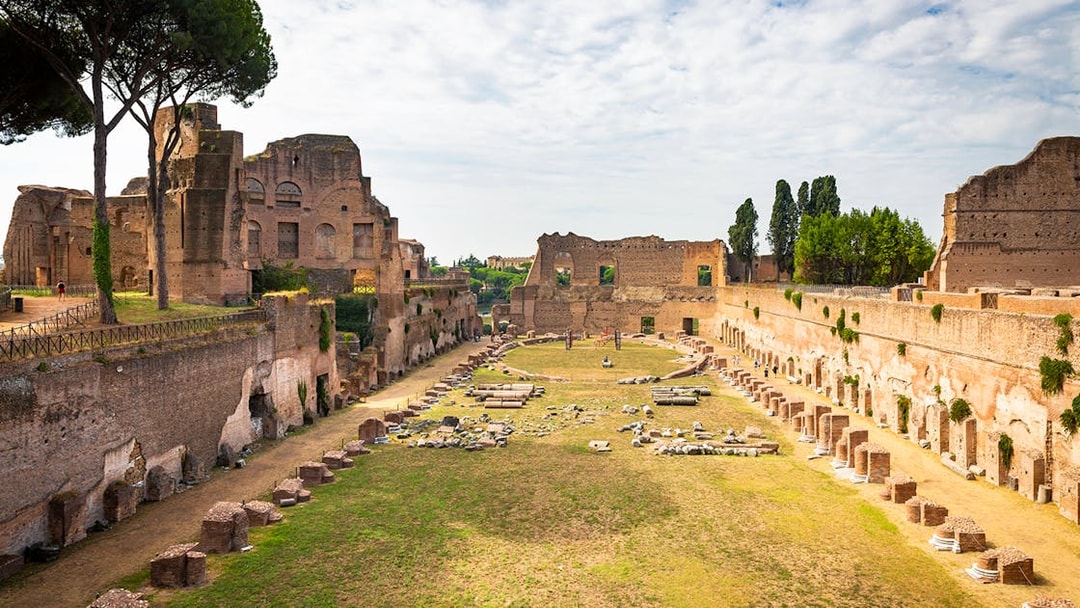 Roman Forum ruins with ancient structures and greenery, view from Palatine Hill, Rome.
