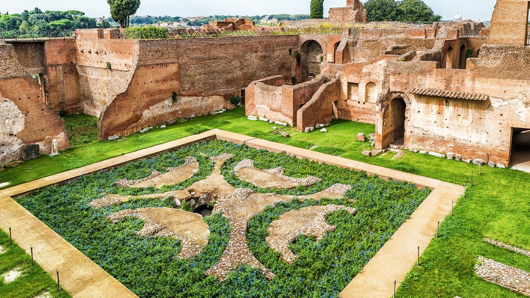 Roman Forum ruins with ancient brick walls and decorative garden, Palatine Hill, Rome.