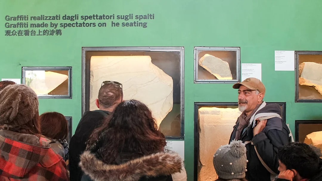 Tour group viewing ancient graffiti at Colosseum exhibit, Rome.