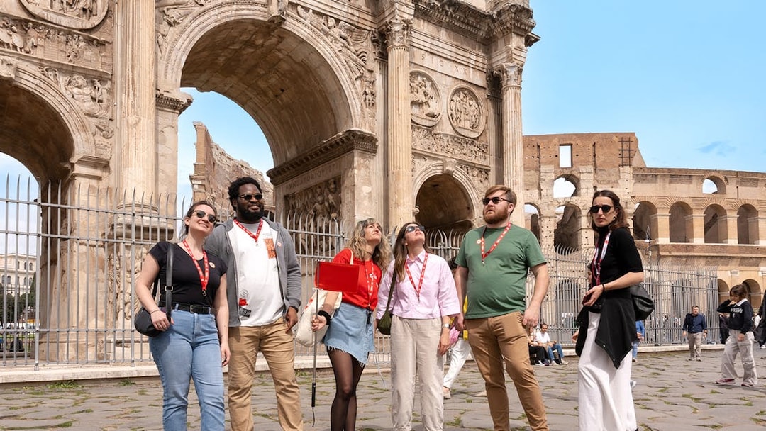 Tour group exploring the Arch of Constantine near the Colosseum in Rome.