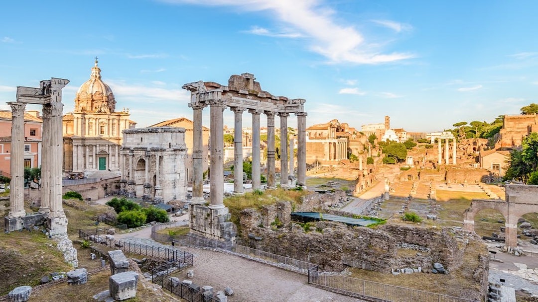 Roman Forum ruins with ancient columns and arches in Rome, Italy.