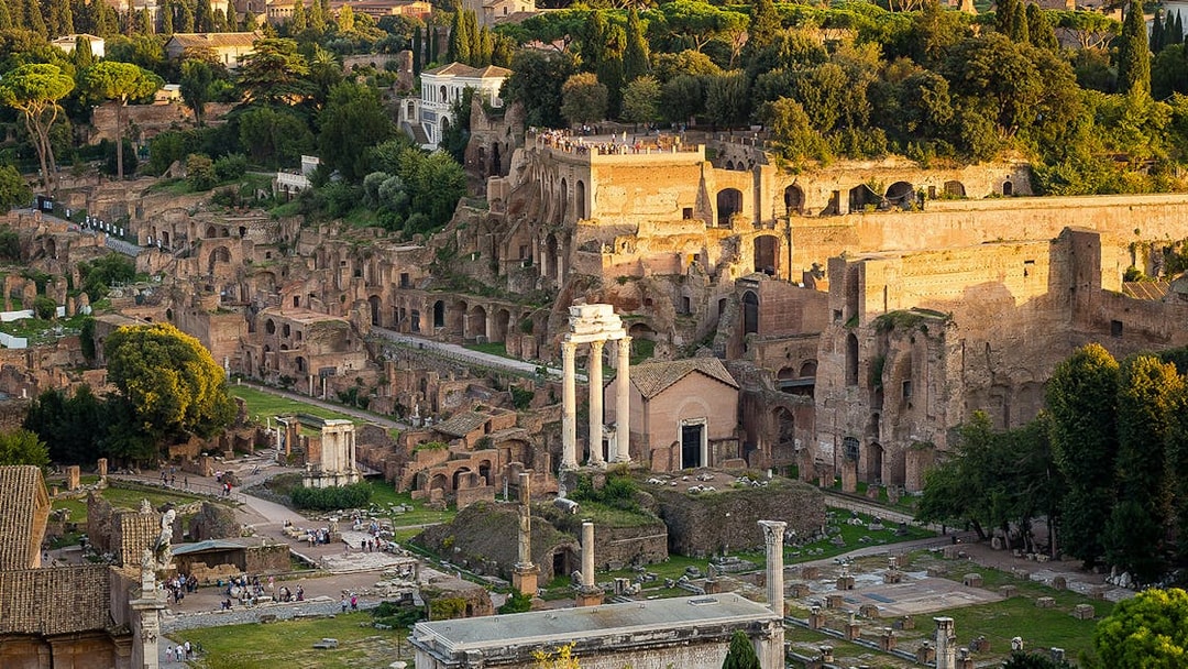 Tourists exploring Palatine Hill with Roman Forum ruins in Rome, Italy.